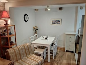 Un comedor con una mesa y sillas blancas, un reloj en la pared y un mueble pequeño.