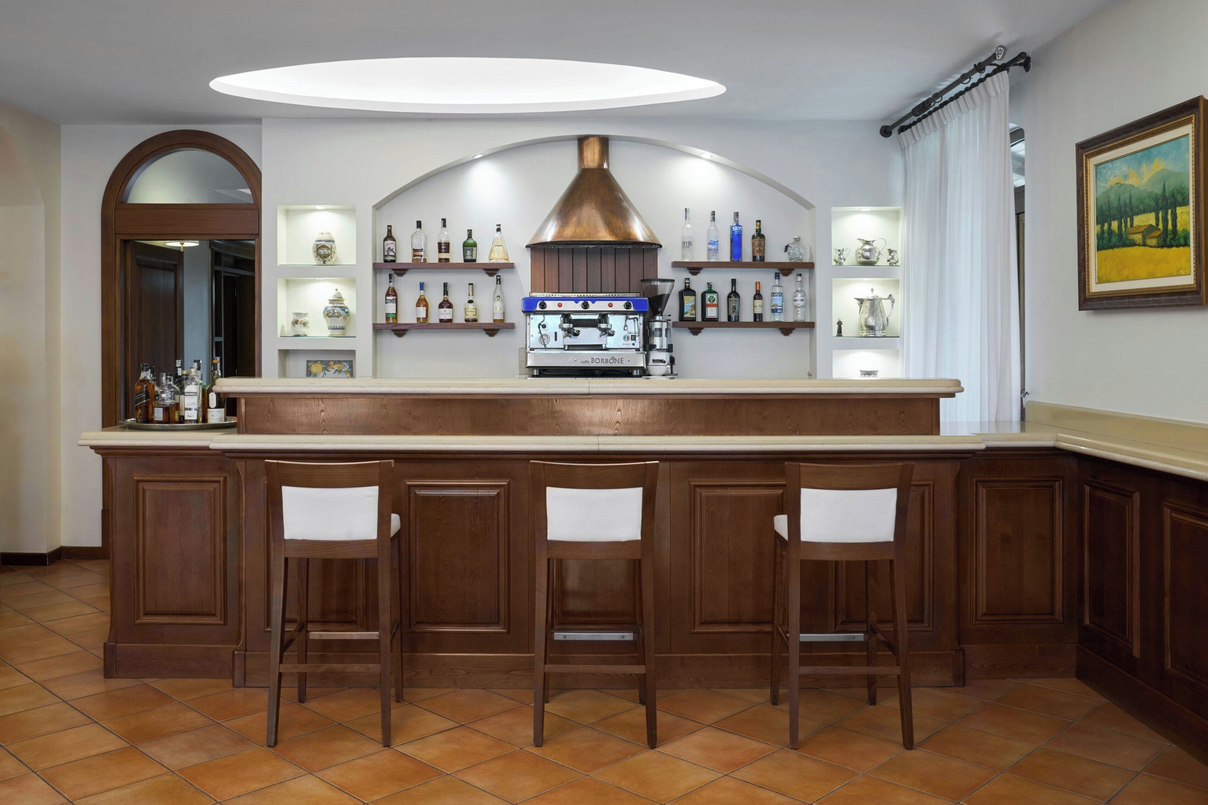 A kitchen with a central island, bar stools, and a built-in espresso machine.