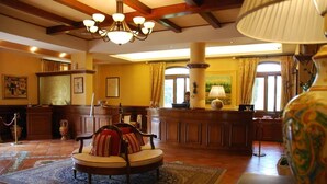 Un vestíbulo con una zona de estar circular, muebles de madera, una araña y un jarrón grande.