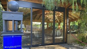 Entrada a un comedor con puertas de vidrio, techo de madera y una planta colgante.