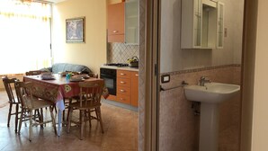 Een keuken met een eettafel, stoelen en een spoelbak.