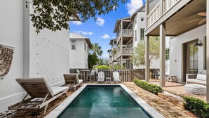 A rectangular pool with lounge chairs and a table, surrounded by a brick patio and a wooden deck. - Private Pool | Walk to Rosemary Beach (Panama City Beach)