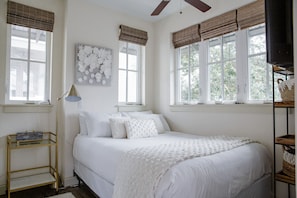 A bedroom with a bed, a bedside table, a lamp, and a wall-mounted artwork.