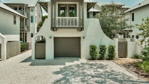A modern two-story house with a garage, a balcony, and a well-maintained front yard. - Carriage House | Walk to Dining and Beach (Panama City Beach)