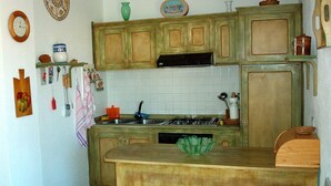 A kitchen with wooden cabinets, a stove, and various kitchen utensils.