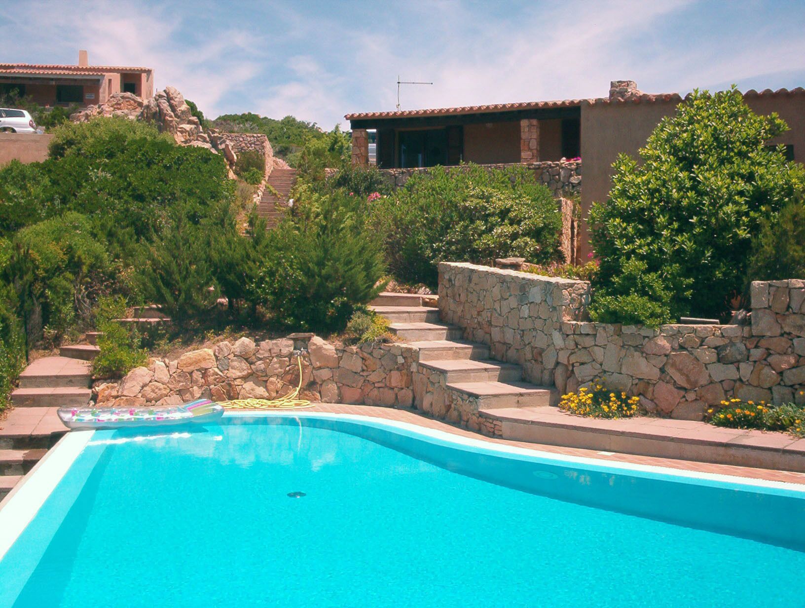 Une piscine avec des marches en pierre menant à un bâtiment doté d’un toit recouvert de tuiles.