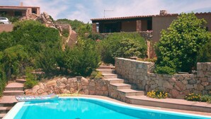 A swimming pool with stone steps leading up to a building with a tiled roof.