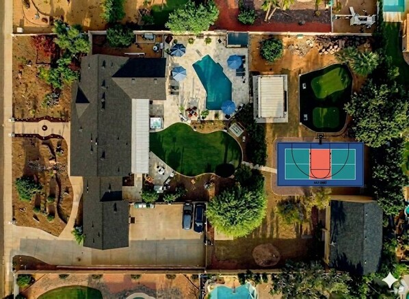 Vista aérea de una propiedad residencial con piscina, cancha de tenis y zonas ajardinadas.