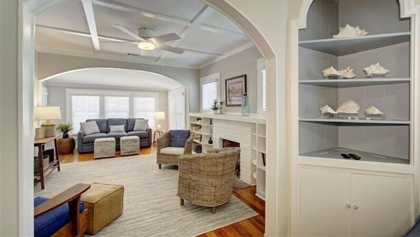 A living room with a sofa, armchairs, a fireplace, and a bookshelf. - Oyster Shell Cottage (St Simons Island)