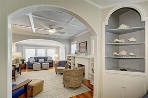 A living room with a sofa, armchairs, a fireplace, and a bookshelf. - Oyster Shell Cottage (St Simons Island)