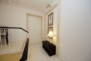 A hallway with a staircase, a door, and a wall-mounted lamp. - AG3 - Casa Rooms (Valletta)