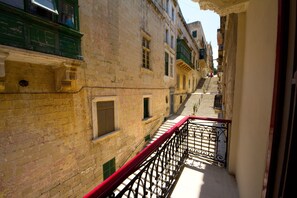 A narrow street with buildings on either side, a red railing, and a staircase leading up. - AG3 - Casa Rooms (Valletta)