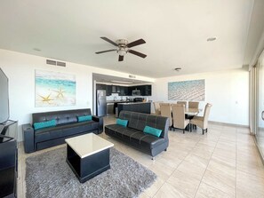 Uma sala moderna com sofá, mesa de centro e um espaço de refeições com cadeiras e mesa.