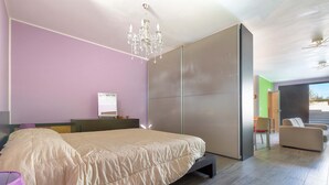 Een moderne slaapkamer met een groot bed, een kroonluchter, een schuifdeur en uitzicht op de omgeving.