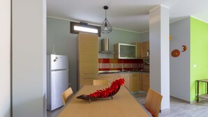 Een moderne keuken met een eethoek, voorzien van een koelkast, magnetron en kastjes.