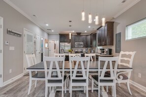 A modern kitchen with dark cabinets, a central island, and pendant lighting. - Vacation Homes at Buckroe Beach! Sleeps 10 (Hampton)