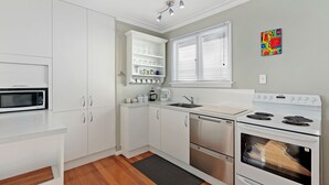 A modern kitchen with white cabinets, a microwave, a stove, and a dishwasher.