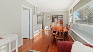 A spacious living area with a dining table, chairs, and a red sofa. There is a kitchen area with cabinets and a refrigerator.