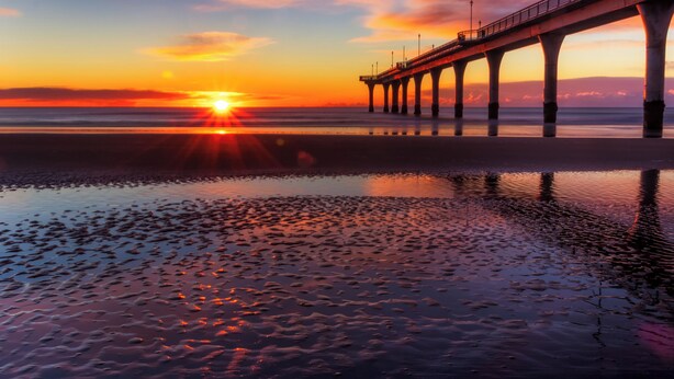 A pier extending over calm waters at sunset.