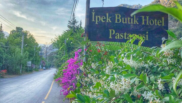 Une enseigne pour l’hôtel Ipek Butik, avec vue sur une route et la végétation environnante.