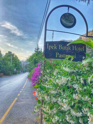 Placa do Ipek Butik Hotel com vista para uma estrada e vegetação ao redor.
