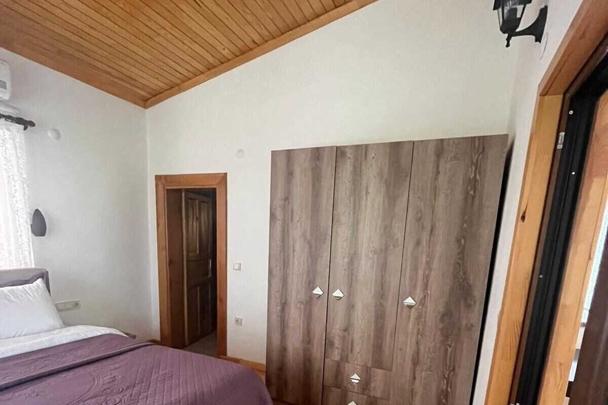 A bedroom with a bed, wooden wardrobe, and a door.