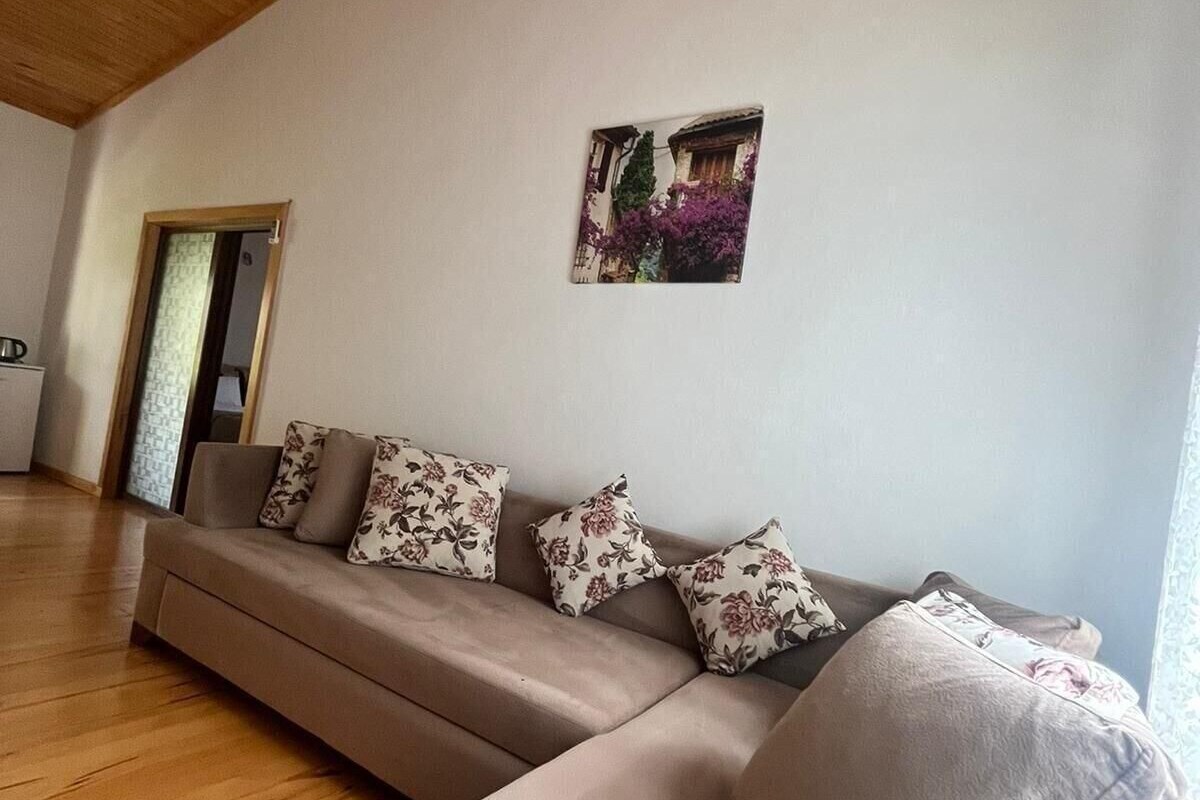 Una sala de estar con techo de madera, un sofá con cojines florales y un cuadro colgado en la pared.
