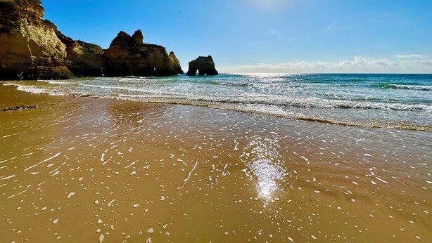 A beach with clear skies, waves, and rocky formations. - ALVOR-ALGARVE SEASIDE  (Alvor)