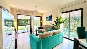 A modern living room with a teal sofa, a dining area, and a view of the garden through large windows. - ALVOR-ALGARVE SEASIDE  (Alvor)