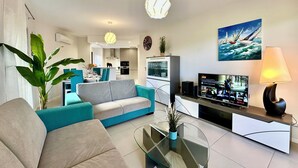 A modern living room with a sofa, a glass coffee table, a TV, and a kitchen in the background. - ALVOR-ALGARVE SEASIDE  (Alvor)