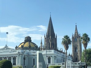 Un bâtiment historique doté d’un dôme et de flèches imposants, vraisemblablement une cathédrale ou une église, avec un ciel dégagé et des palmiers au premier plan.