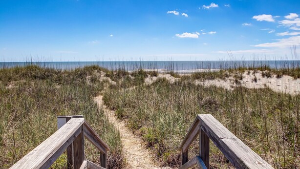 A wooden boardwalk leading to a beach with sand dunes and sparse vegetation. - Oceanfront | Spacious Deck | Beautiful Views | Seagate Condo (Fernandina Beach)