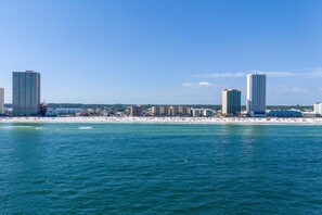 A coastal cityscape with high-rise buildings, a beach, and a clear blue sky.