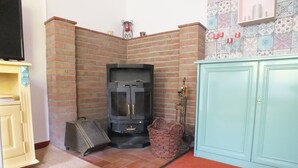 Una habitación con chimenea de ladrillo, televisor, aparador y pared con diseño.