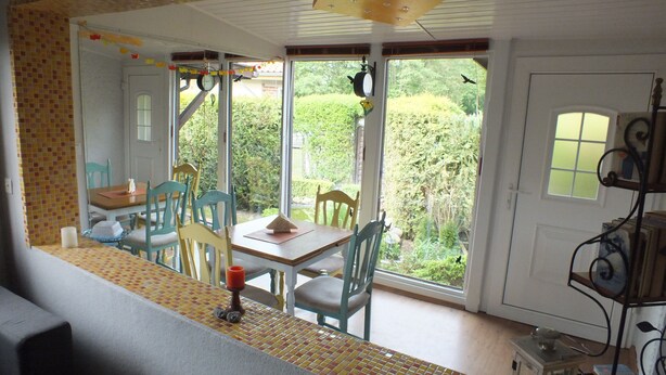 Un comedor con una mesa y sillas, una ventana que ofrece vistas a zonas verdes, y una puerta con un pequeño ventanal.
