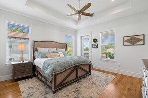 A bedroom with a bed, nightstand, and ceiling fan.