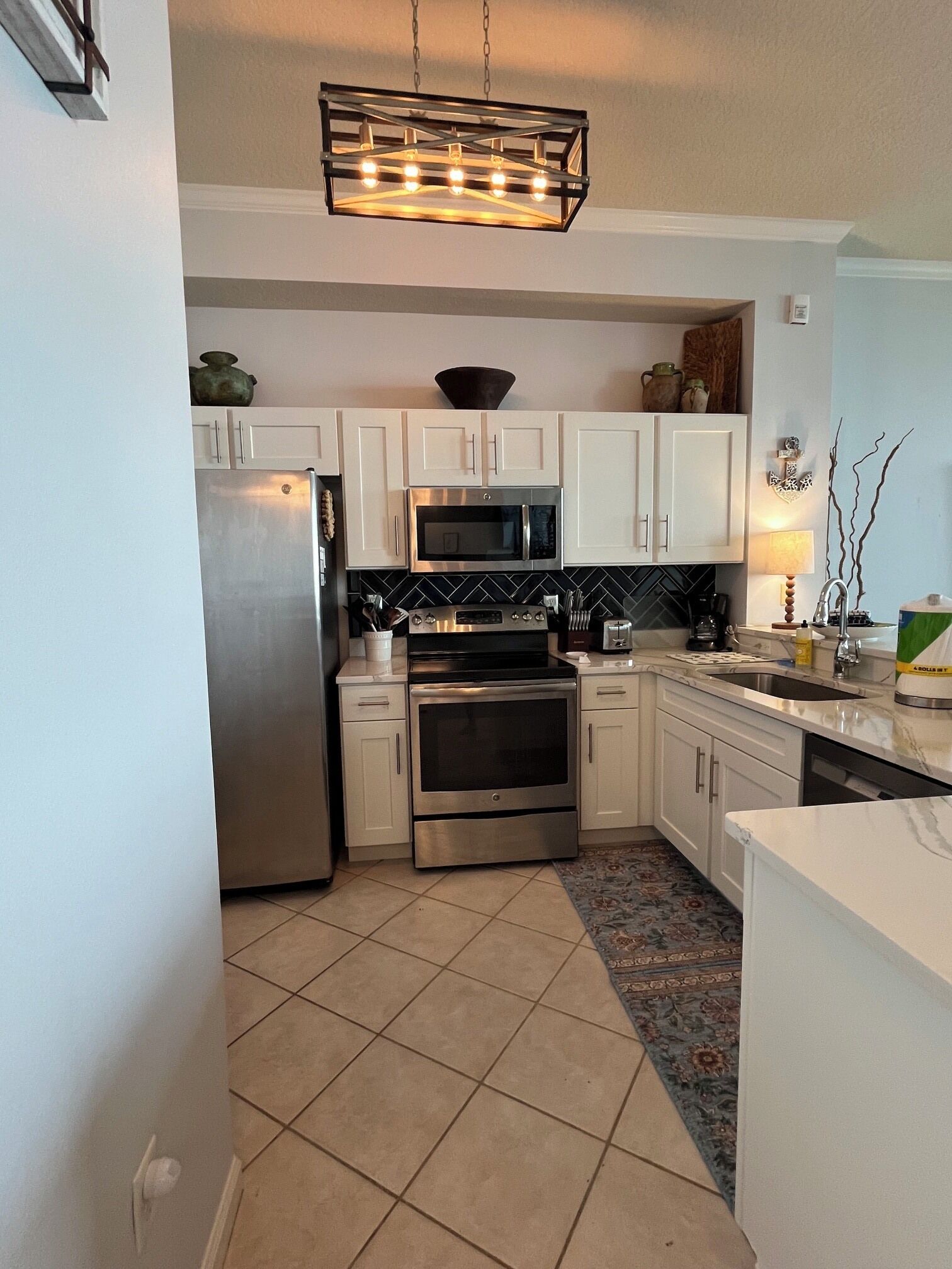 A modern kitchen with white cabinets, stainless steel appliances, and a black backsplash.