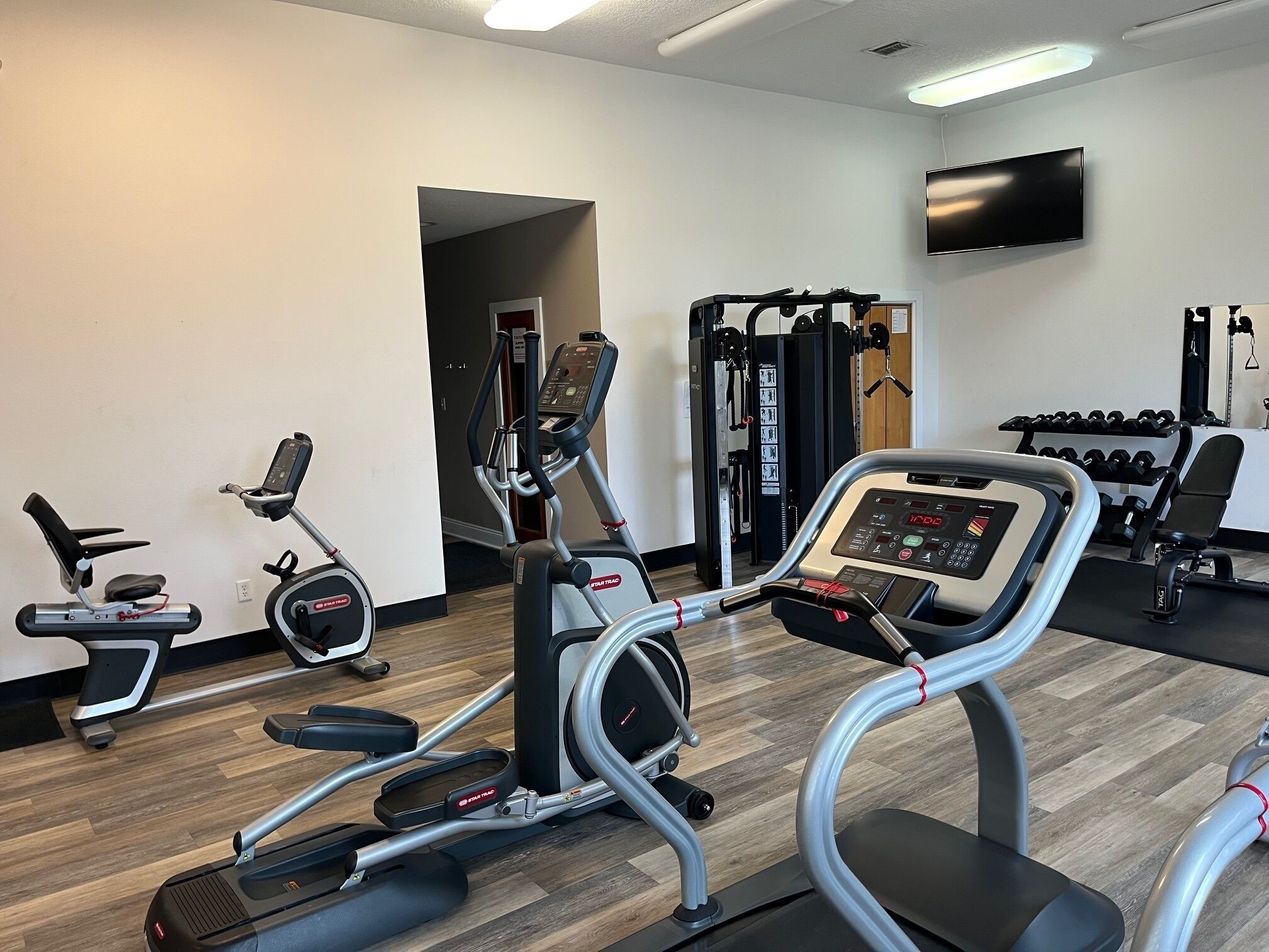 Ein Fitnessstudio mit Laufbändern, einem Ergometer und Gewichten.