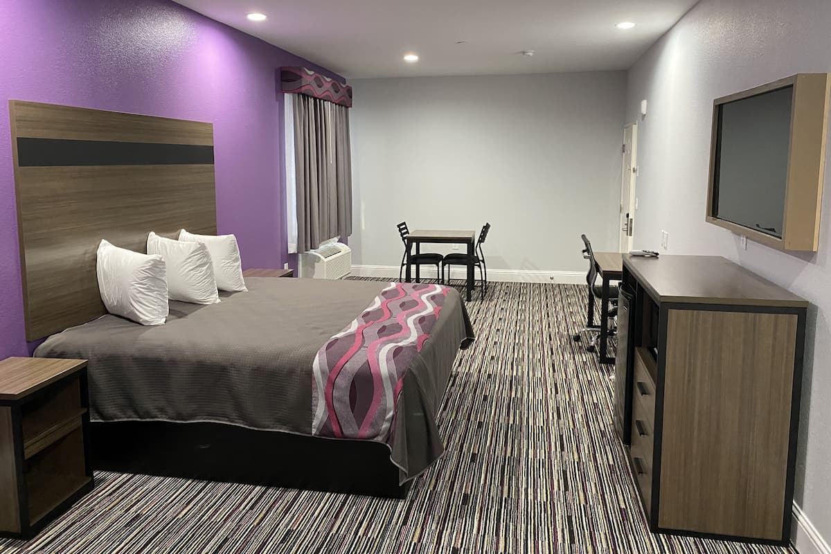 A hotel room with a bed, a desk, a chair, a television, and a wardrobe.