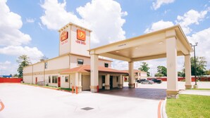 A hotel with a prominent sign indicating it is now open, a covered parking area, and a clear sky with clouds. - Palace Inn Crosby (Crosby)