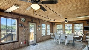 Un intérieur en bois comprenant un coin repas, des ventilateurs de plafond et de grandes fenêtres.
