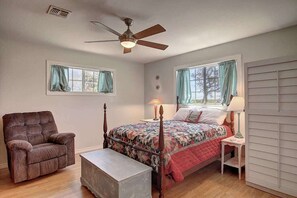 Ein Schlafzimmer mit einem Himmelbett, einem Sessel, einem Nachttisch und einem Deckenventilator.