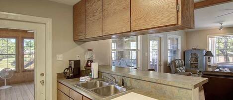 Una cocina con armarios de madera, una encimera, un fregadero y un ventilador.