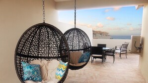 Two hanging chairs with cushions, a dining table, chairs, and a view of the sea. - Beachfront Modern Loft with Large Private Terrace (Isabela)