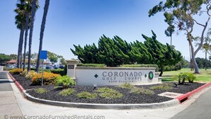 Schild für den Coronado Golfplatz mit einer angelegten Grünfläche, die Palmen und Sträucher zeigt.