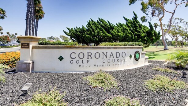Schild für den Coronado Golfplatz, mit blauem Himmel und umgebender Bepflanzung.