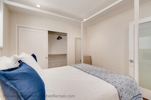 Una camera da letto con un letto, un armadio, uno specchio e una porta.