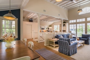 A spacious living area with a dining table, sofas, and a kitchen in the background.