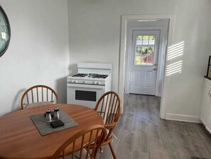 A dining area with a wooden table and chairs, a white stove, and a door leading to a backyard. - Large Fenced Yard, Pool Table, Disney Central (Fullerton)