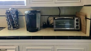 Een keuken met een koffiezetapparaat, broodrooster en waterkoker op het aanrecht.